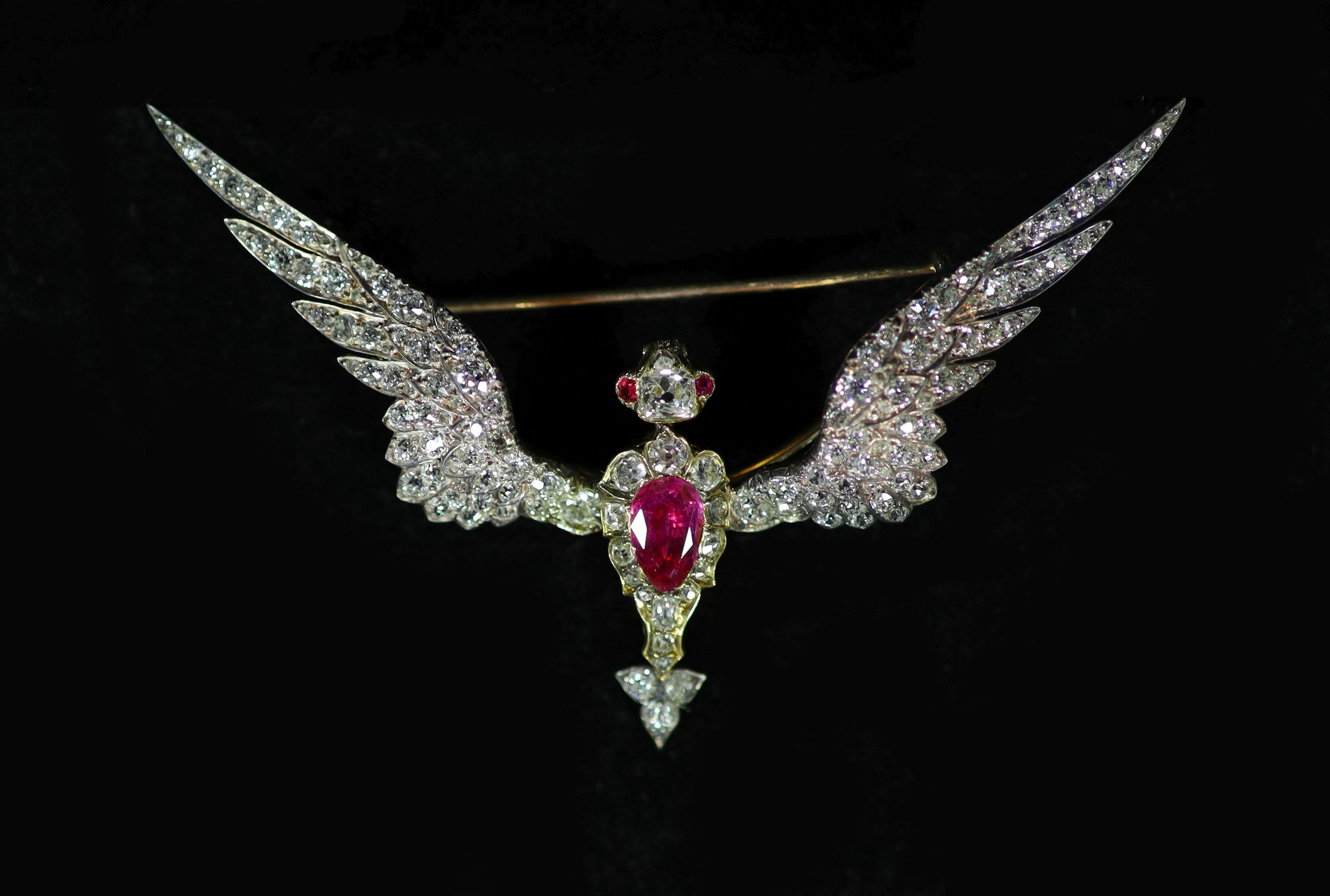 A late Victorian gold, foil backed pear cut ruby and old mine cut diamond encrusted brooch, modelled as a Phoenix